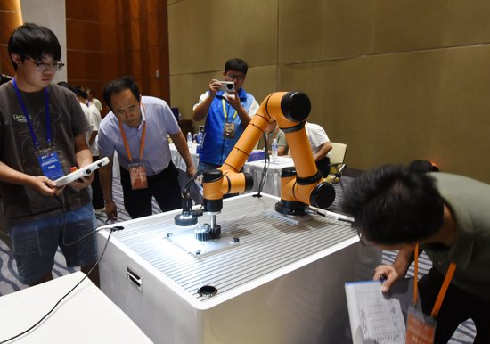  △ 2025年中国大学生机械工程创新创意大赛智能精密装配赛京津冀鲁联赛现场，评委对参赛选手进行实操调试评比。