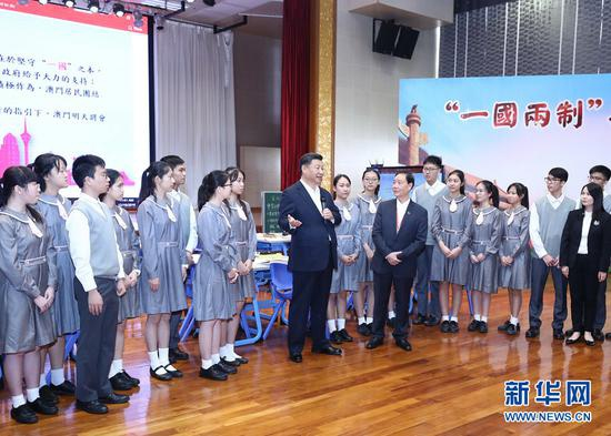  2019年12月19日，国家主席习近平在澳门特别行政区行政长官崔世安陪同下，来到位于澳门黑沙环的政府综合服务中心和濠江中学附属英才学校，同澳门市民和师生亲切交流。在濠江中学附属英才学校观摩以“‘一国两制’与澳门”为题的中国历史公开课后，习近平走到学生中间即席发表重要讲话。 新华社记者 鞠鹏 摄
