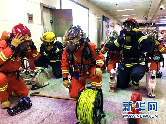 演习中的消防员（中）准备利用消防救生照明线进行路线标注。新华网 黄浩 摄