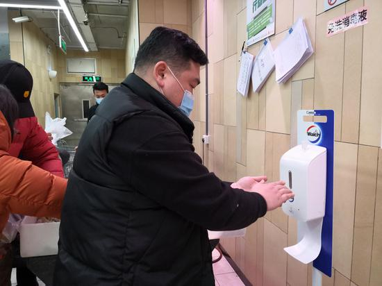 市民在超市选购冷链食品，货架上有手套和消毒液