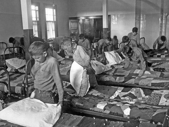 ▲ 1950年，加拿大一所原住民寄宿学校的原住民儿童在整理床铺。