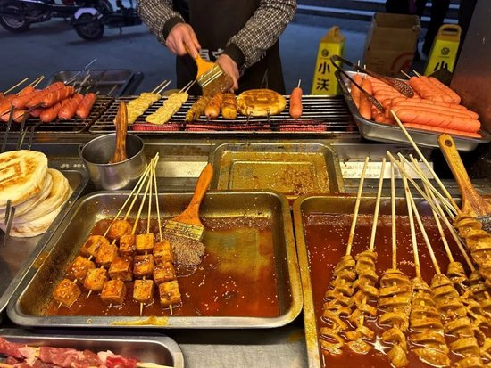 路边摊出售的小吃与十几年前相比变化不大，摊主正在制作食物。