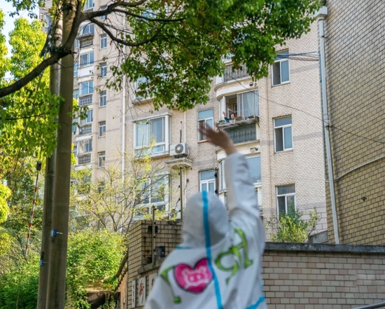  ▲在一次送货后，何艳君和收货人隔空挥手。受访者供图