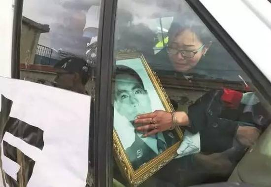 杨茜将丈夫遗像搂在怀里，含泪送丈夫回家