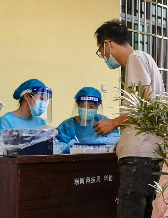 吞静（中）生前在核酸检测现场协助核对人员信息 新华社 发