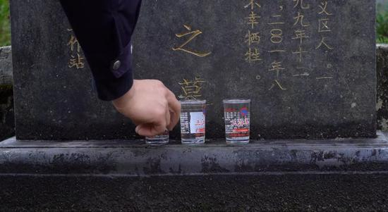  民警们在祭奠烈士，扫落叶、敬烟酒，酒是当地产的小杯分装的白酒。新京报记者&nbsp; 徐雪飞 摄