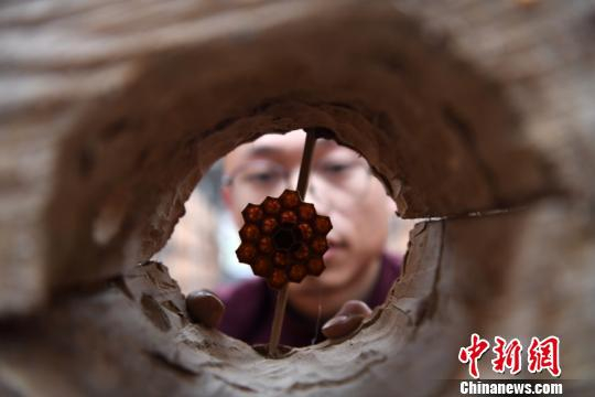 韦国良查看刚修好的胡蜂巢桶。王炳真 摄