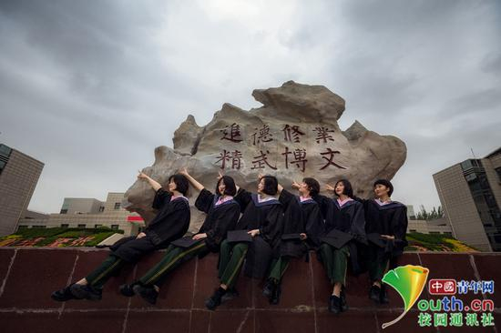 毕业女学员的背后是我院校训石，她们指向远方，那是未来的战位，挥洒汗水的地方，必将在全心全意为人民服务中书写无悔的军旅人生。中国青年网通讯员 褚龙 摄