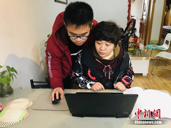 王晓丽母子一起看成长档案 张芹 摄