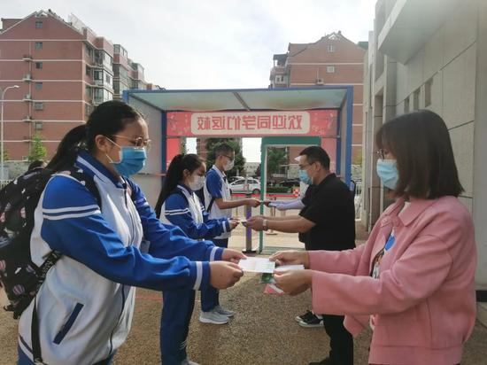 返校进行时，老师们站在校门口热情地欢迎着每一位同学。