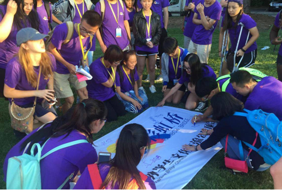 　　中美学生在“彩虹桥”旗帜上签名