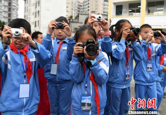 图为5月31日，摄影希望小学摄影小社团的学生拿着爱心相机在校园摄影学校“六一”节活动。　张斌 摄