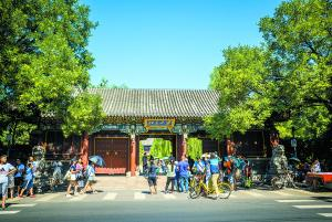 在北京大学东门，来自各地的游客竞相与北大校门合影留念。@视觉中国