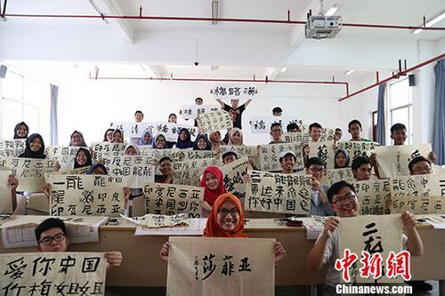 资料图：7月29日，东盟国家学生和自己的书法作品合影留念。 中新社发 瞿宏伦 摄