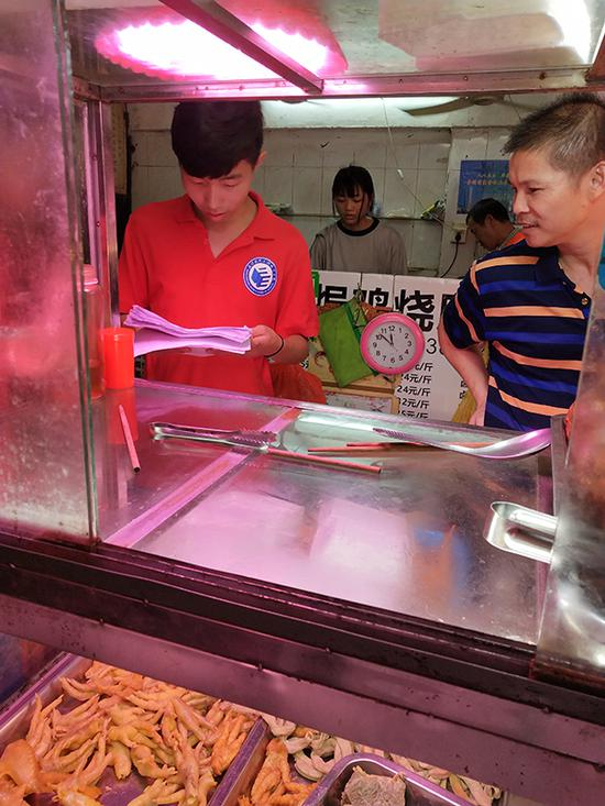 队员程浩请教一位开店二十余年的老板，讨论盐焗鸡美食文化的传承