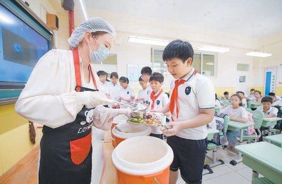 白家庄小学老师正在给学生发放餐食。 本报记者 潘之望摄