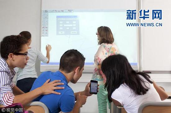 一群法国年轻人在教室玩手机。