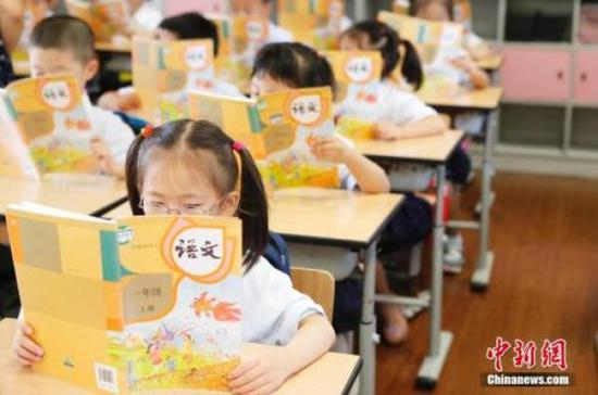 孩子们正在认真阅读《语文》教材。 资料图