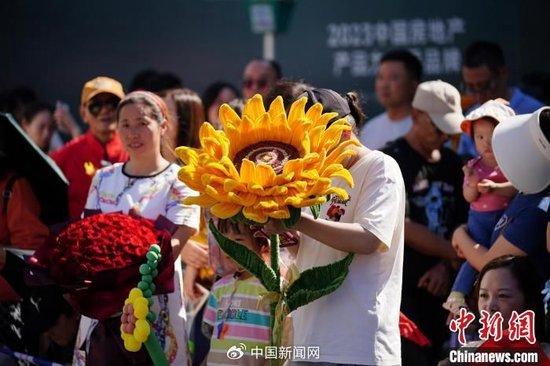 6月8日，云南省昆明市，考生家长手持寓意“一举夺魁”的巨大向日葵迎接孩子。当日，云南2024年高考结束。刘冉阳 摄
