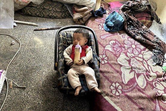 当地时间2024年5月25日，加沙地带汗尤尼斯，一名7个月大的巴勒斯坦婴儿在被毁的学校里睡觉，奶瓶里装的是他母亲Hanan Burgut在食物短缺期间准备的扁豆汤。