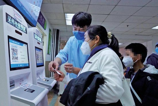 北京儿童医院，家长在自助机前报到。北京儿童医院供图