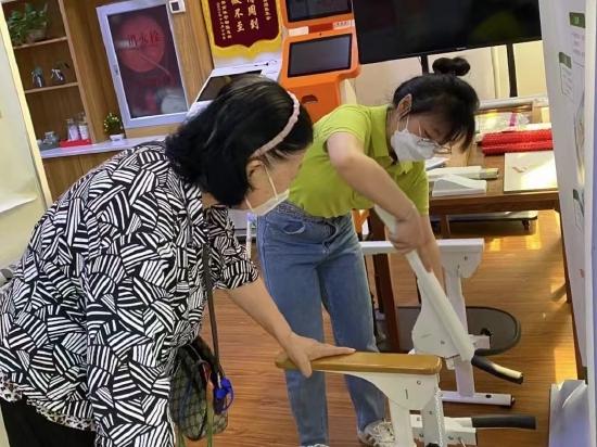 介助咨询师贾秋然在社区向老人介绍马桶助力架。受访者供图