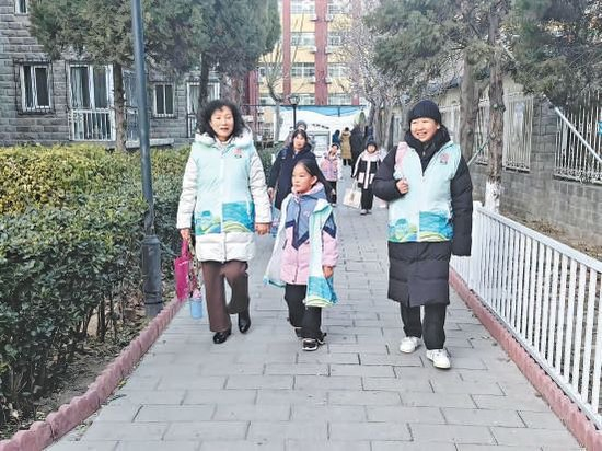 志愿者赵巍（左）和社区工作者所慧接小紫依放学。清友园社区 供图