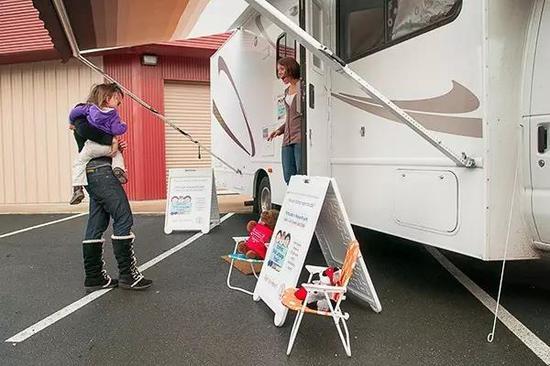 Jillian Maes（研究队员）在和参与实验项目的一对母女打招呼