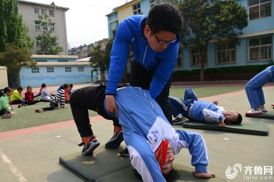图为老师帮助学生矫正动作。