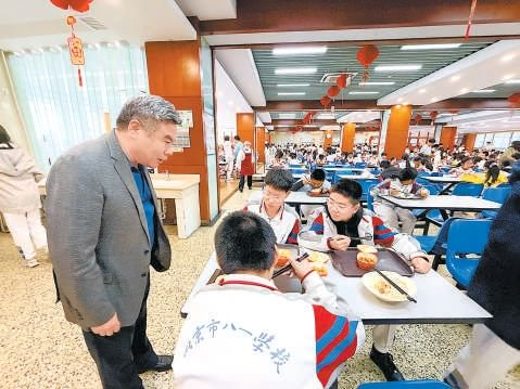 北京市八一学校副校长刘荣铁（左一）陪餐后与学生们交流。 本报记者 李祺瑶 摄