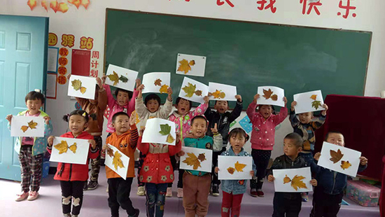 乡村幼儿园的孩子们举起自己用树叶做的贴画