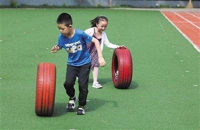 7月23日，方庄第二小学，小朋友在玩滚轮胎游戏。本版摄影/新京报记者 李木易