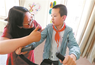 　　在无锡市广新小学融合教育资源中心，梁溪区特教指导中心资源教师陈向华指导小过进行康复训练，夸赞他有进步。