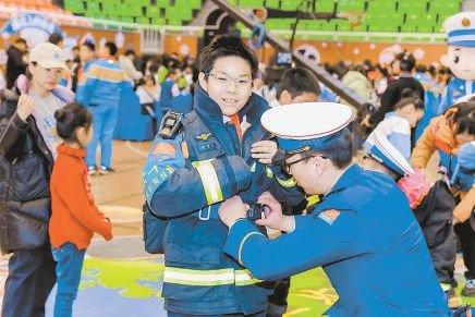 学生在活动现场参与消防战斗服体验活动。