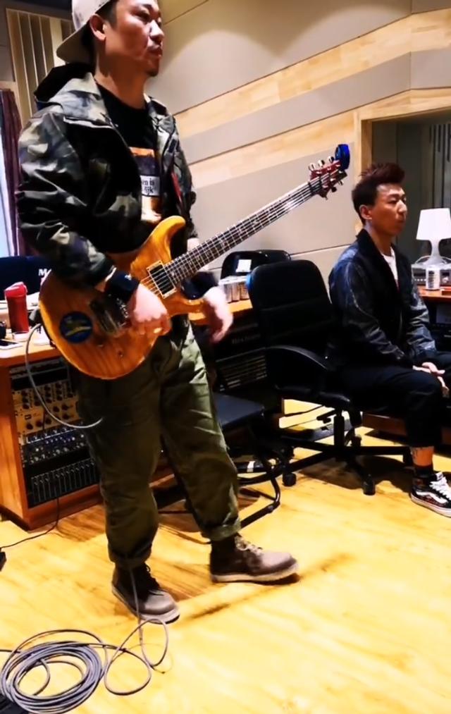 视频中一位吉他手正在弹吉他,陈羽凡坐在吉他手不远处听着音乐,并随着