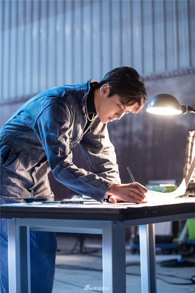 手绘制设计图纸的他还时不时拿着修理工具弯腰组装汽车部件,眼神专注