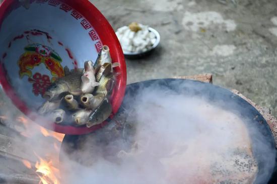 ▲ 黔东南，侗族人在室外将鱼下入酸汤锅中。图/视觉中国