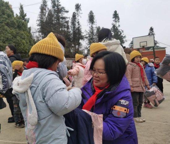快鱼服饰有限公司爱心基金会长曾裕琇女士为小朋友穿上捐赠的棉衣