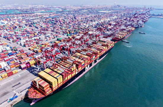 2025年4月15日，山东青岛港，货轮在装卸外贸集装箱。