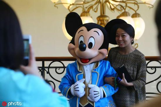 在迪士尼乐园里与米老鼠合影的游客