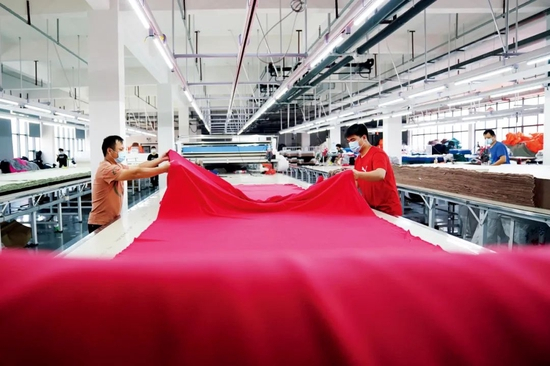 　5月3日，江西一些企业陆续复工复产。在南昌市的一家制衣公司里，工作人员在车间进行拉布工序。图/新华
