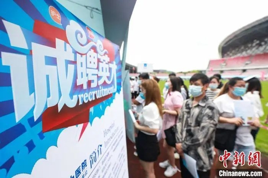 资料图：招聘会上，一家医院的展位吸引求职者排队求职。瞿宏伦 摄