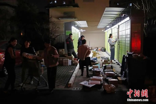 资料图：民众正在小区广场上取快递。殷立勤 摄