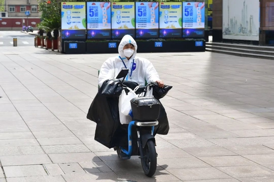 　上海，全副武装的快递小哥在运送物品