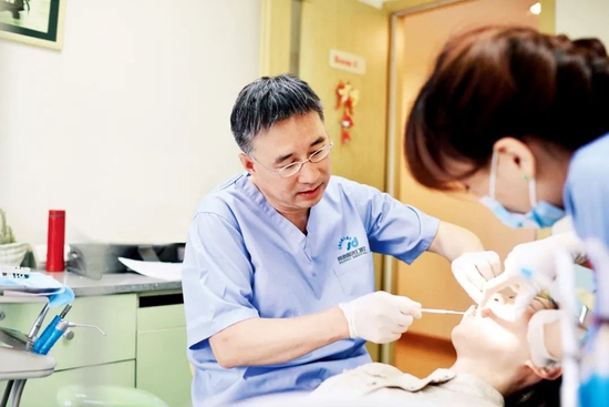 “赛德阳光口腔”创始人周彦恒正在检查患者牙齿情况。图/受访者提供