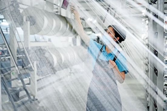 4月12日，福建泉州石狮市的一家纺织企业，工人在车间内忙碌。图/新华