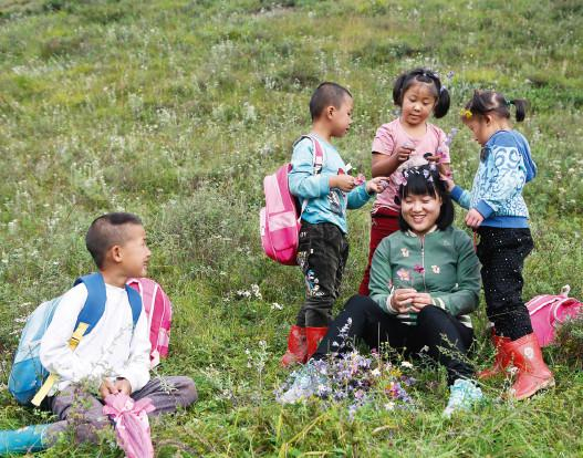 2017年9月5日，甘肃文县椿树坪小学，孩子们摘了野花戴在老师张军燕头上。（赖鑫琳 / 摄）