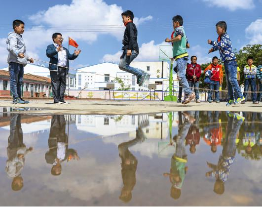 　2016年5月，宁夏同心县下马关镇中心小学，白星老师为玩跳绳的孩子喊加油。（赖鑫琳 / 摄）