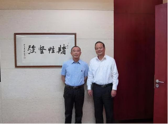 　·曾毓群（右）和他办公室里有名的那幅字。