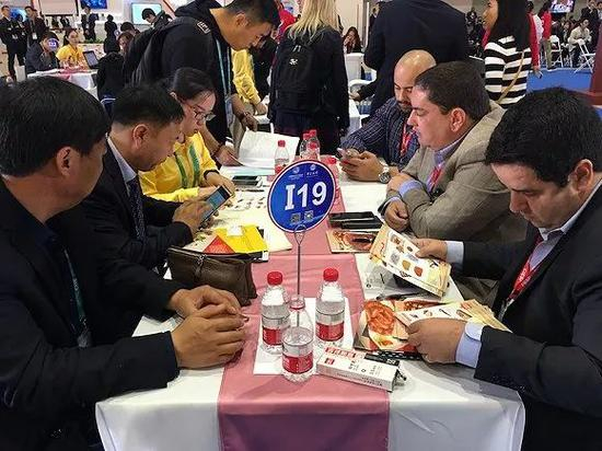 来自甘肃的聂大田和黄杰正在与巴西展商洽谈。摄影：刘素楠